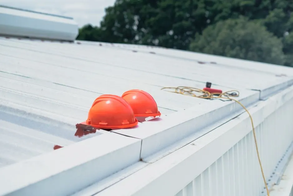 Red hard hats and safety equipment on a metal roof, emphasizing construction safety.