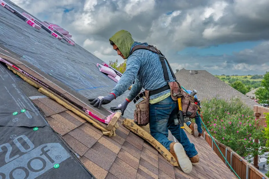Roofers working on shingle installation on a home in Fort Worth, Texas under blue skies.