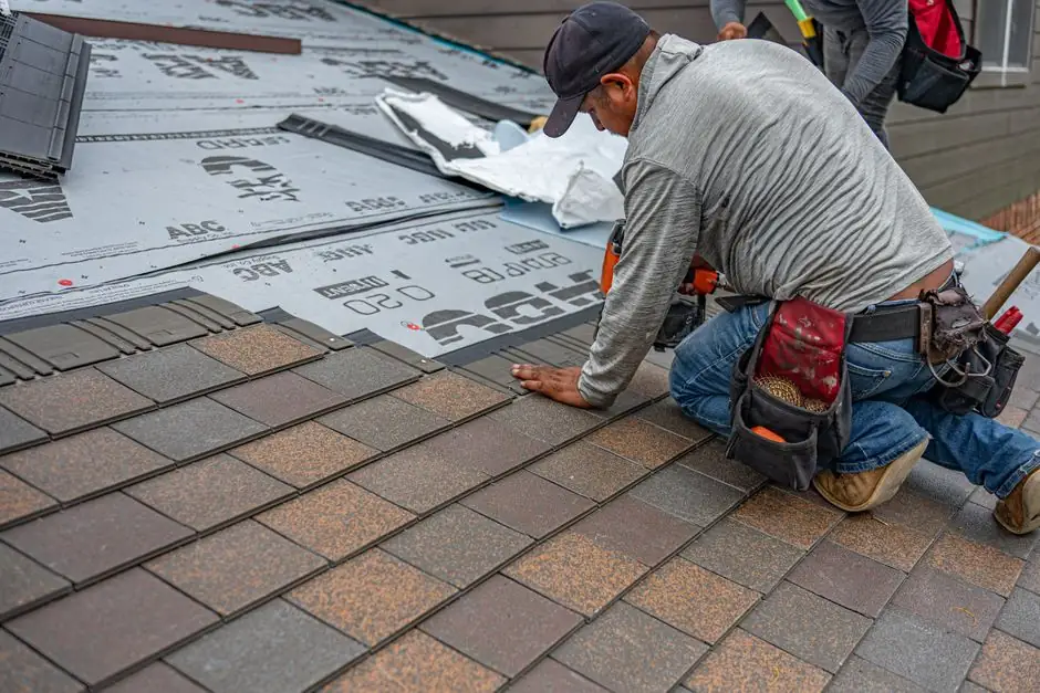 Skilled roofer installing asphalt shingles, ensuring quality home renovation.